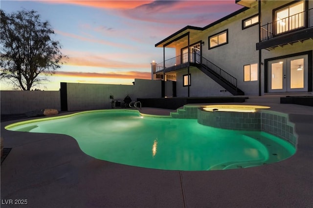 pool at dusk with french doors and an in ground hot tub