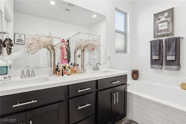 bathroom with vanity and tiled bath