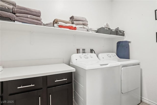 clothes washing area with cabinets and washing machine and clothes dryer