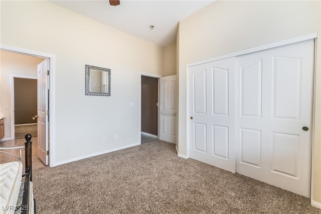 unfurnished bedroom with high vaulted ceiling, carpet, a closet, and baseboards