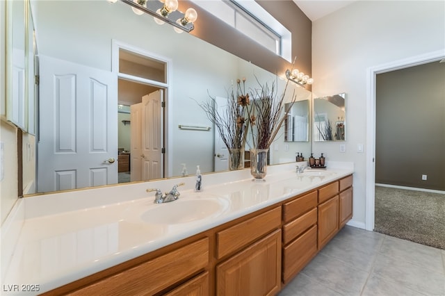 bathroom with baseboards, double vanity, a sink, and tile patterned floors