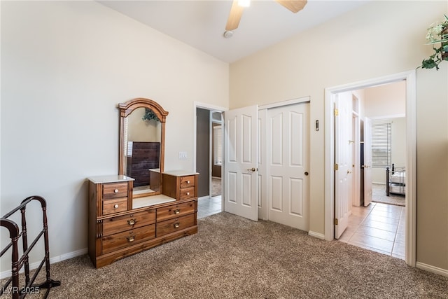 carpeted bedroom with a ceiling fan, a closet, baseboards, and tile patterned floors