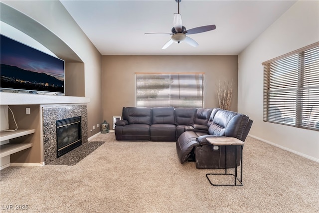 living room with carpet floors, baseboards, a ceiling fan, and a high end fireplace