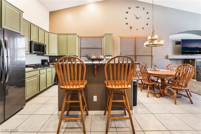 kitchen with a center island, light tile patterned floors, appliances with stainless steel finishes, high vaulted ceiling, and green cabinetry