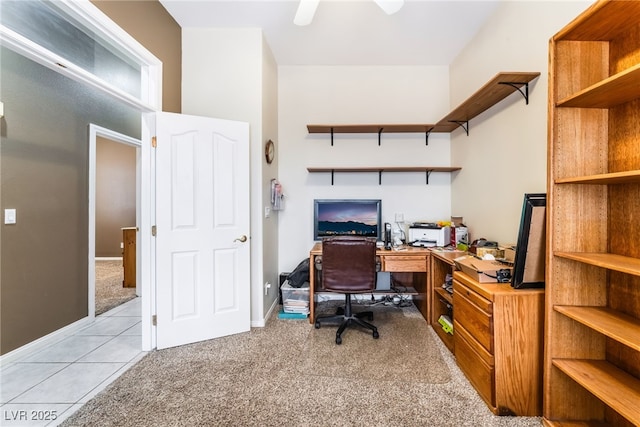 office space with baseboards, light tile patterned flooring, a ceiling fan, and light colored carpet