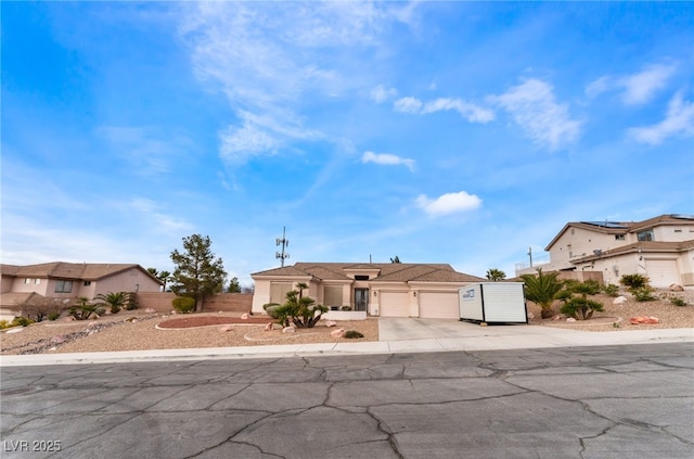 view of front of property with driveway, an attached garage, fence, and stucco siding