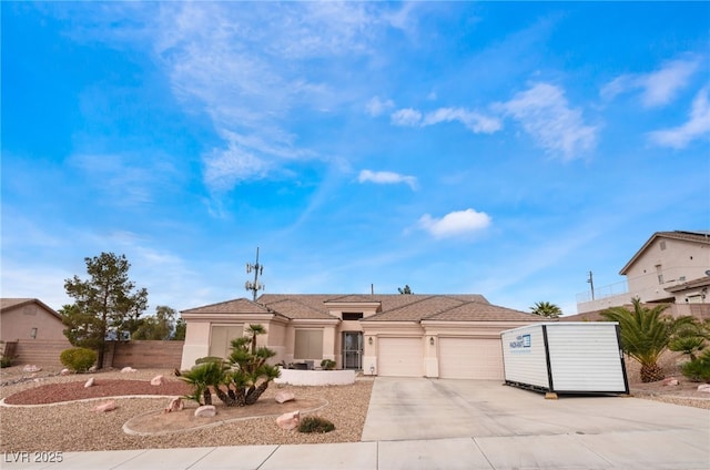 view of front of house with driveway, a garage, fence, and stucco siding