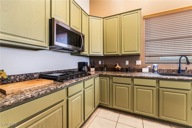 kitchen with stainless steel microwave, light tile patterned flooring, a sink, gas cooktop, and green cabinetry