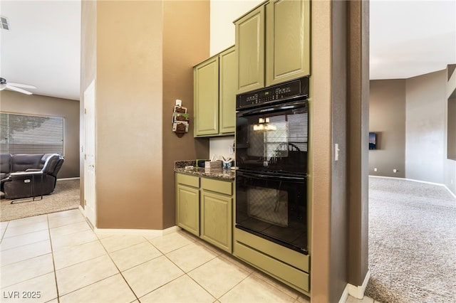 kitchen featuring light tile patterned floors, light colored carpet, dobule oven black, a ceiling fan, and green cabinets