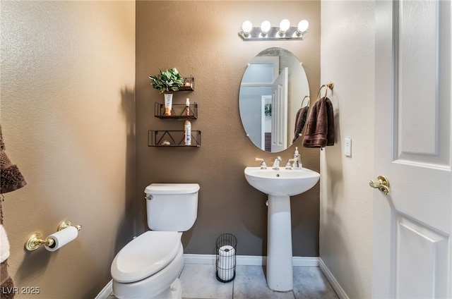 half bathroom featuring tile patterned flooring, toilet, and baseboards