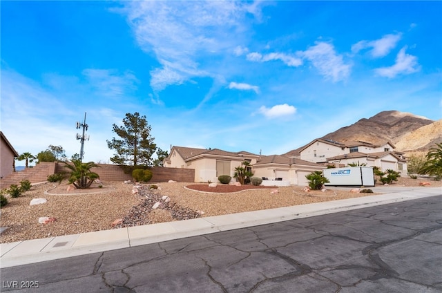 view of front facade featuring fence, driveway, an attached garage, and stucco siding