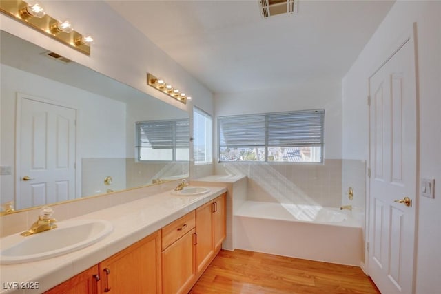 bathroom featuring vanity, a bath, hardwood / wood-style floors, and a healthy amount of sunlight