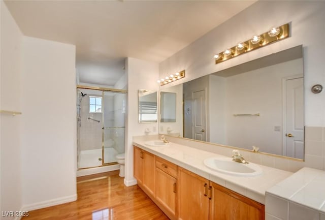 bathroom featuring vanity, toilet, a shower with shower door, and hardwood / wood-style floors