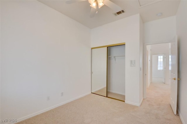 unfurnished bedroom featuring ceiling fan, light colored carpet, and a closet