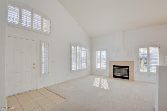 foyer entrance with light carpet, a fireplace, and high vaulted ceiling