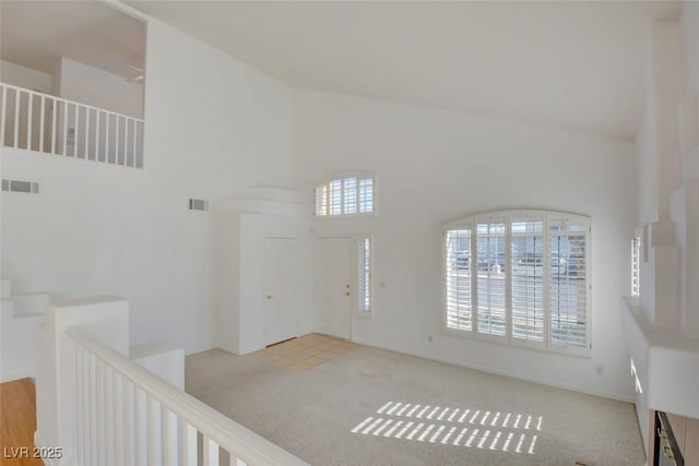 carpeted foyer with high vaulted ceiling