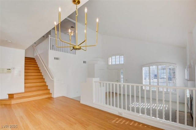 stairway featuring wood-type flooring, a high ceiling, and a notable chandelier