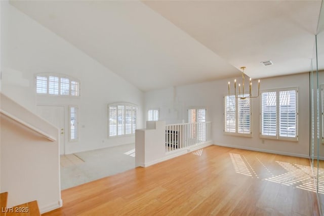 unfurnished living room featuring a notable chandelier, high vaulted ceiling, and light wood-type flooring