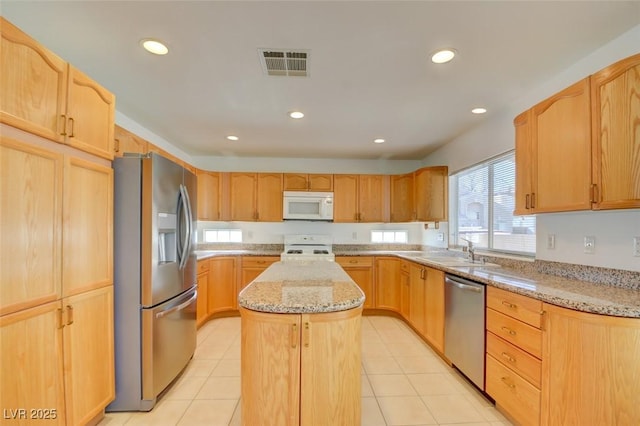 kitchen featuring stainless steel appliances, light stone countertops, sink, and a kitchen island