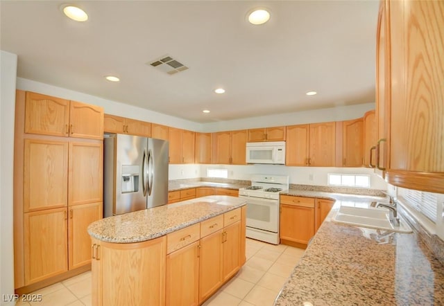 kitchen with light stone countertops, sink, light brown cabinetry, and white appliances