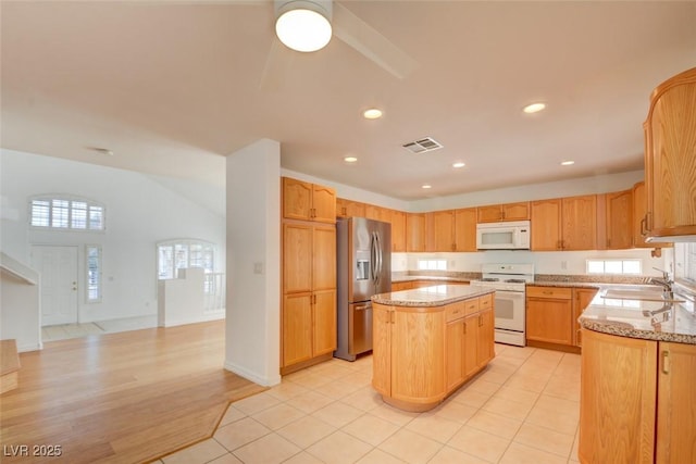 kitchen with white appliances, light stone countertops, sink, and a kitchen island