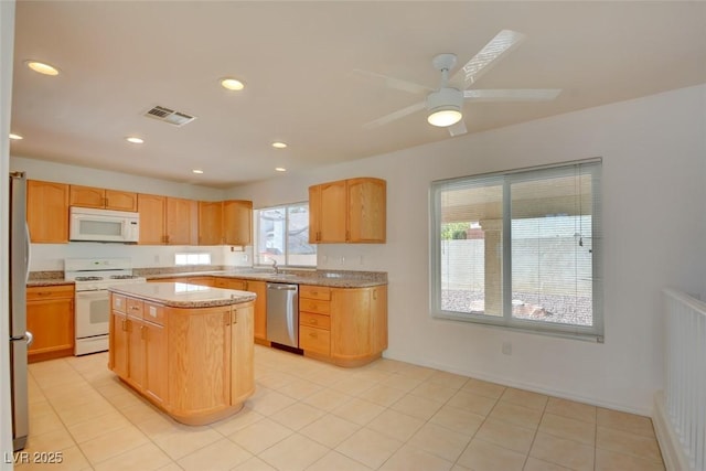 kitchen featuring sink, appliances with stainless steel finishes, a center island, light stone counters, and light brown cabinets