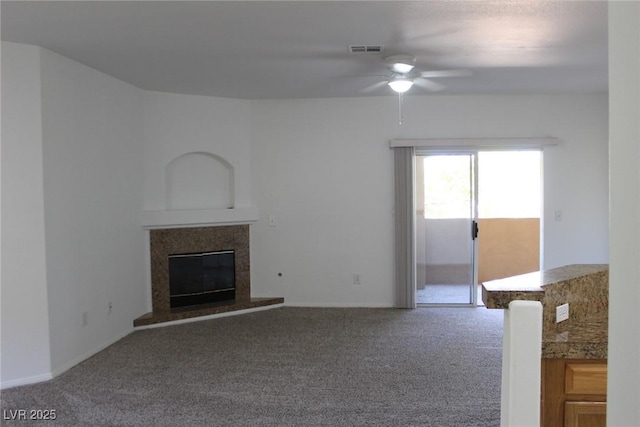 unfurnished living room with ceiling fan, carpet, and a fireplace