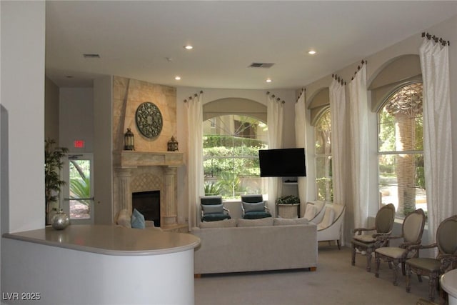 living room with light colored carpet, a healthy amount of sunlight, and a tile fireplace