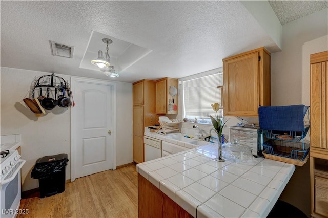 kitchen featuring decorative light fixtures, white appliances, tile counters, and light hardwood / wood-style floors