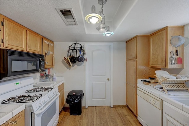 kitchen featuring white appliances, tile countertops, hanging light fixtures, and light hardwood / wood-style flooring