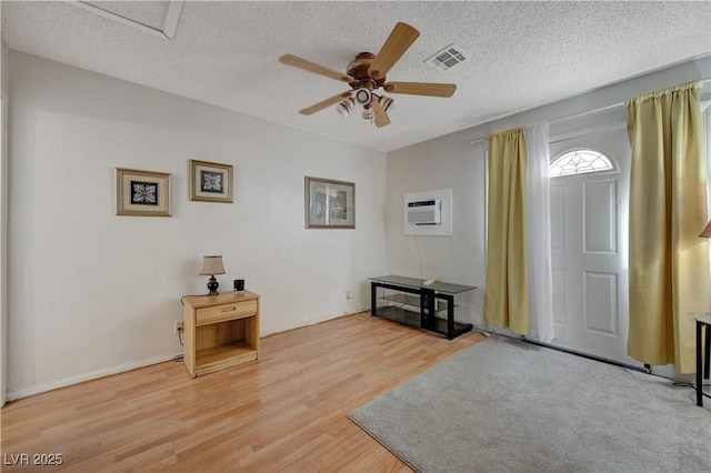 entrance foyer with hardwood / wood-style floors, an AC wall unit, a textured ceiling, and ceiling fan