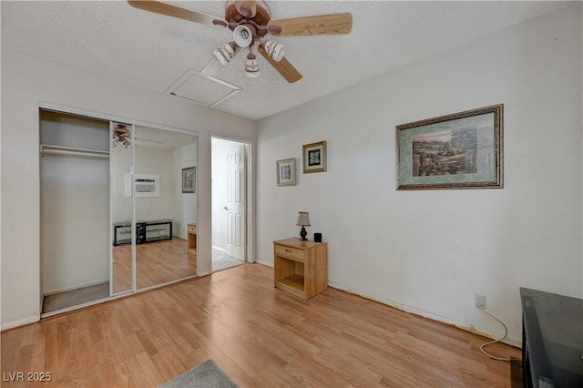 unfurnished bedroom featuring ceiling fan, a closet, a textured ceiling, and light wood-type flooring