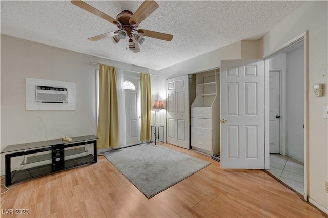 interior space with wood-type flooring, a wall mounted AC, ceiling fan, and a textured ceiling