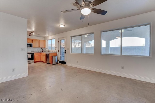 unfurnished living room featuring concrete floors, a sink, baseboards, and ceiling fan