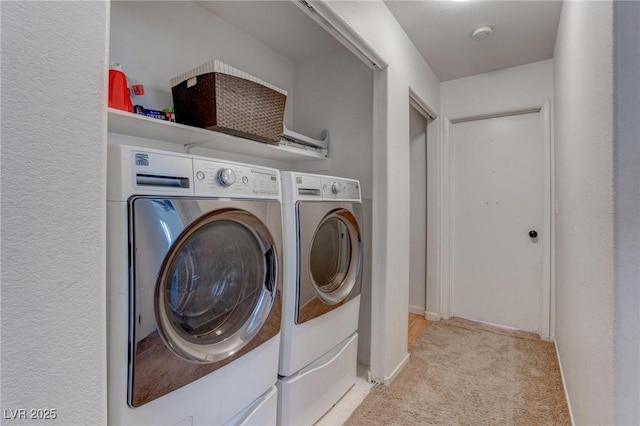 clothes washing area with washing machine and dryer, laundry area, and light colored carpet