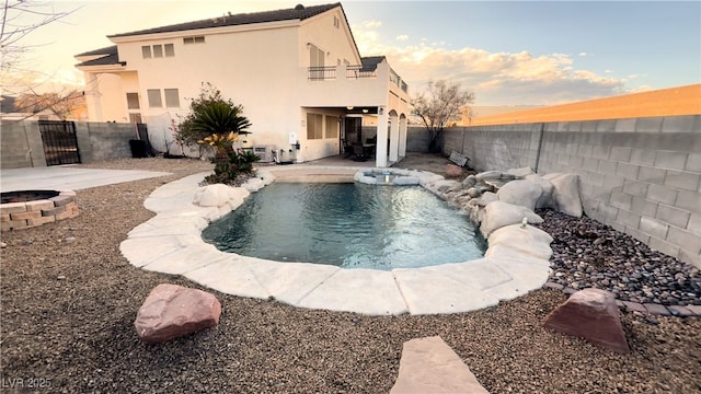 pool at dusk featuring pool water feature and a patio area