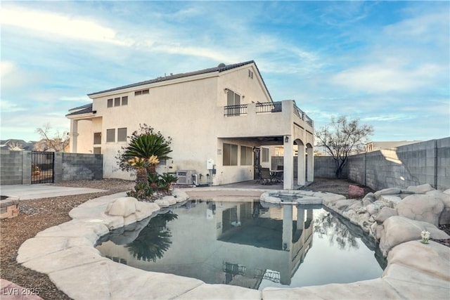 back of property with a patio, a fenced backyard, a balcony, a gate, and stucco siding