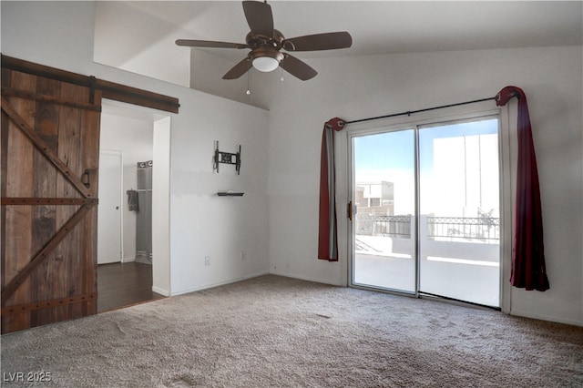 carpeted spare room with lofted ceiling, a barn door, and a ceiling fan