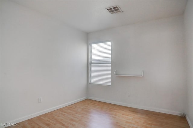 unfurnished room featuring light wood-style floors, visible vents, and baseboards