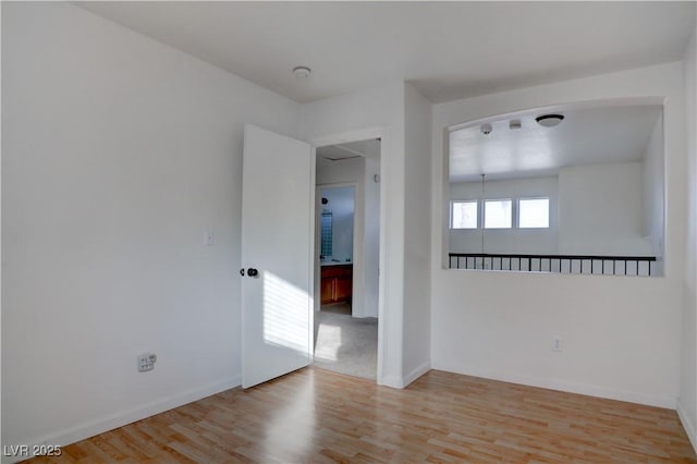 empty room featuring light wood-type flooring and baseboards