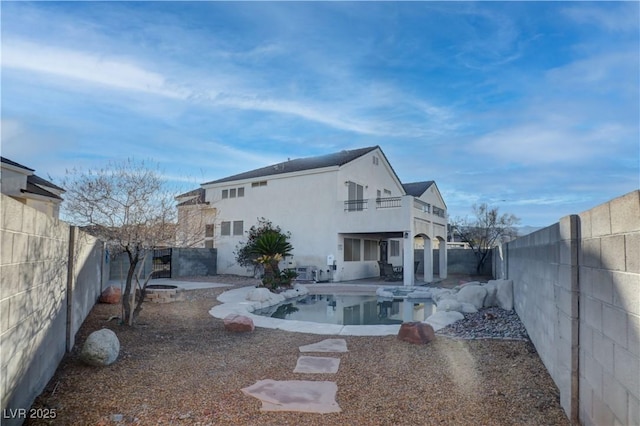 back of house featuring a balcony, a fenced backyard, a patio, and stucco siding