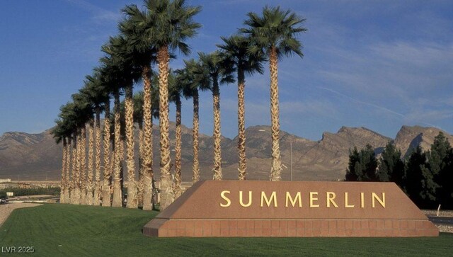 community sign with a mountain view and a lawn