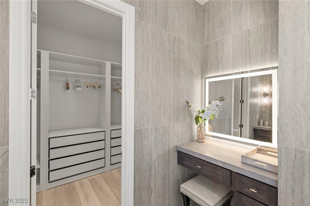 bathroom featuring vanity, hardwood / wood-style floors, and tile walls