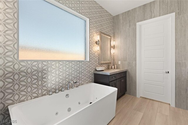 bathroom featuring a tub to relax in, a healthy amount of sunlight, hardwood / wood-style floors, and vanity