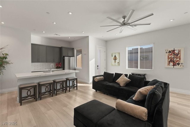 living room with sink, light hardwood / wood-style flooring, and ceiling fan