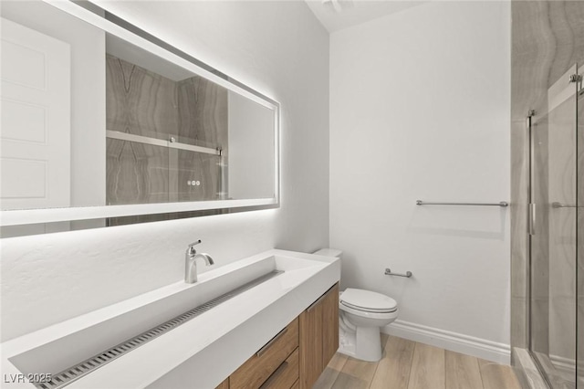 bathroom featuring a shower with door, vanity, hardwood / wood-style floors, and toilet