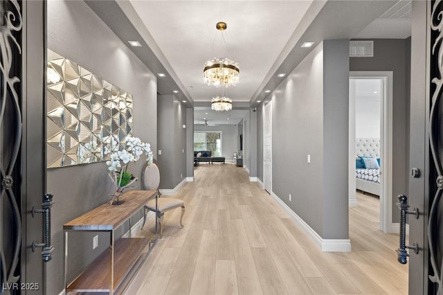 hallway with light hardwood / wood-style floors and a notable chandelier