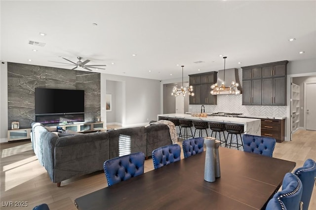 dining area featuring ceiling fan with notable chandelier and light wood-type flooring