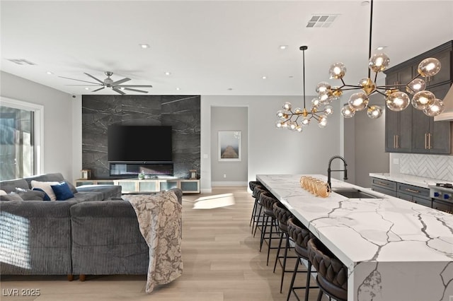 living room with sink, light hardwood / wood-style flooring, and ceiling fan