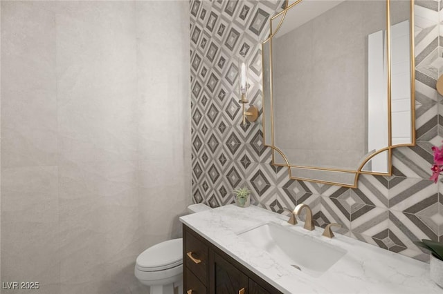 bathroom with vanity, tile walls, and toilet